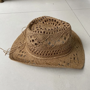 Detail of hand-woven brown straw cowboy hat featuring intricate hollow weave and decorative cord