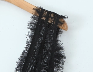 Détail de la dentelle cil noire et des paillettes sur la robe de soirée avec col en V profond