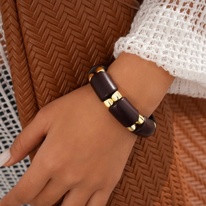 Close-up of a vintage bracelet with dark brown beads and gold accents on a wrist