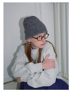 Detailed texture of gray wool blend knit hat with ribbed pattern on a female model