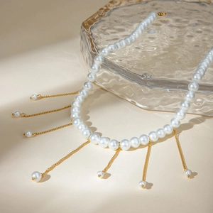 Detail of white pearl necklace with golden metal fringe tassels on water-ripple tray