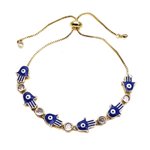 Detailed macro view of gold-plated Hamsa hand and blue enamel evil eye adjustable bracelet