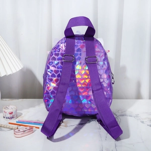 Close-up of holographic purple mini backpack with embossed heart texture on marble surface