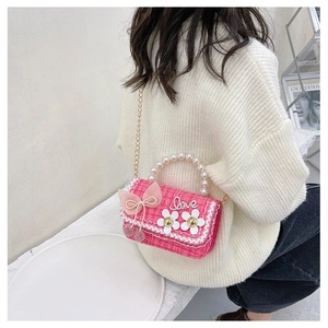 Detail of rose pink tweed bag featuring pearl handle, lace trim, and bow decoration