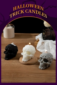 Three skull candles in black, white and grey on wood with soft festive lighting