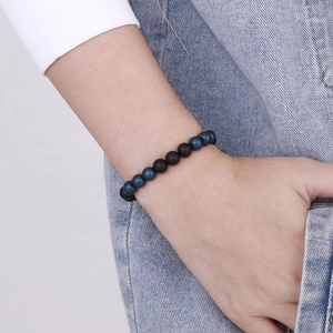 Close-up of blue cat eye and matte black agate bead bracelet on a model wrist