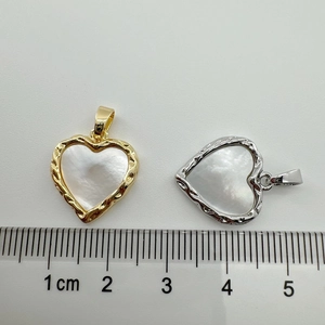 Detailed view of heart pendants in gold and silver showing 2cm width against a ruler