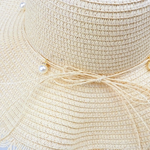 Women's straw sun hat with wavy brim, pearl pendants and ribbon bow detail in beige