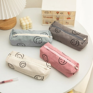 Corduroy smiley face pencil cases in four colors on a cozy desk setup for students