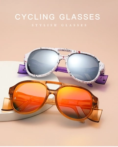 Dual stylish cycling glasses with white ink splatter and amber frames on props