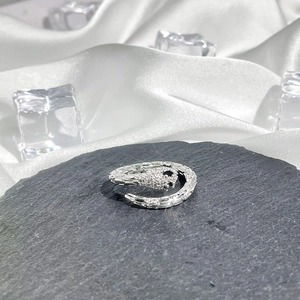 Macro shot of a silver snake-shaped ring with textured details on a black stone base
