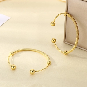 Minimalist 18K gold plated mesh open cuff bracelets with ball ends on a textured surface