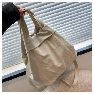 Detail of a beige nylon tote bag featuring soft pleated design and comfortable wide handles