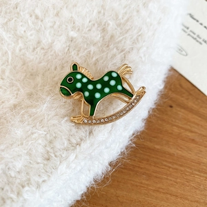Macro view of a green rocking horse brooch with white dots and sparkling diamonds