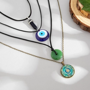 Detail of multi-layered ethnic necklaces with evil eye, crystal point, and mandala charms