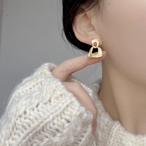 Close-up of minimalist brushed gold double hoop earrings worn on a model's ear