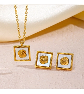 Detail view of gold stainless steel necklace and earrings with white shell rose charms