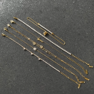 Detailansicht von sechs goldenen Edelstahlarmbändern mit Zirkonia und Love-Anhängern