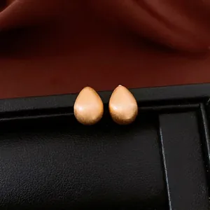 18k gold plated teardrop stud earrings with matte brushed finish on luxury velvet display