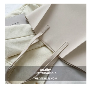 Detail shot of neat stitching on the handle connection of the beige leather tote bag