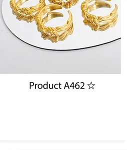 Close-up of gold-plated twisted woven rings displayed on a reflective mirror surface