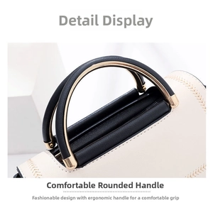 Detail view of beige faux leather bag with V-shaped stitching and black gold handle