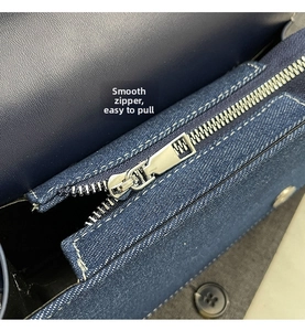 Vue détaillée de la fermeture éclair en métal argenté sur un sac à bandoulière en denim bleu
