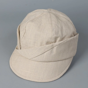 Close-up of beige linen blend fabric texture and stitching on a minimalist newsboy cap
