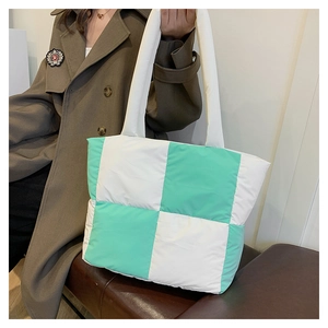 Detail of mint green and white quilted checkerboard tote bag worn by a model
