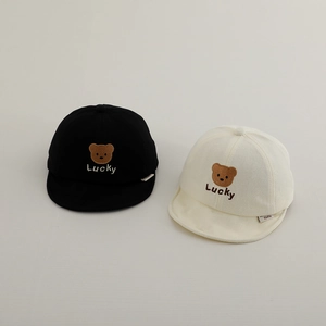 Detail of embroidered bear and Lucky text on soft cotton baby caps in black and cream