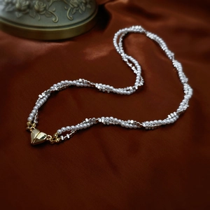 Detail of double-layer pearl necklace with golden magnetic heart clasp on satin fabric