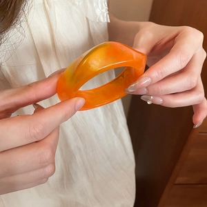 Detail shot of orange marbled acrylic resin bangle showing the smooth glossy finish