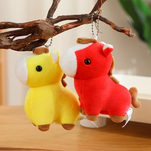 Close-up of yellow and red plush horse keychains hanging on a rustic branch decoration