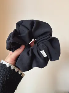 Close-up of black oversized scrunchie with silver glitter dots and Hand Made label