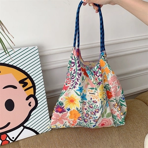 Detail of floral tote bag with blue woven rope handle and woven brand label