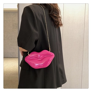 Macro shot of a hot pink lip-shaped acrylic crossbody bag with a golden chain strap