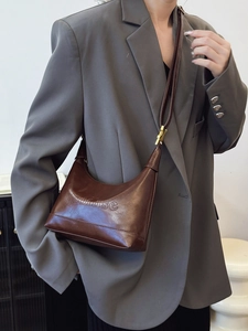 Brown leather crossbody bag with embossed lettering styled with a grey blazer