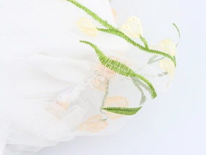 Détail de la broderie délicate de tulipes jaunes sur tulle blanc pour robe de soirée
