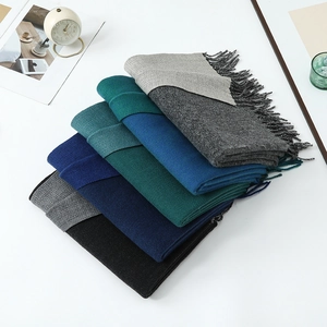 Detail of soft cashmere-like scarves with fringe edges in grey, blue, and green tones