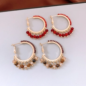 Detailed view of red and brown beaded hoop earrings with bohemian woven ethnic style