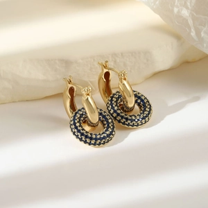 Close-up of gold hoop earrings with pavé blue cubic zirconia in a circular design