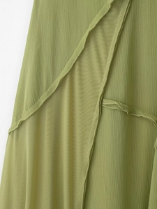 Dettaglio del patchwork in chiffon a pieghe verde e mesh trasparente sull'abito