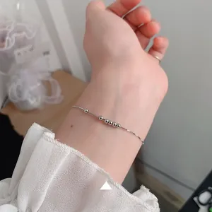 Detail of minimalist 925 sterling silver bead bracelet worn on wrist with lace sleeve