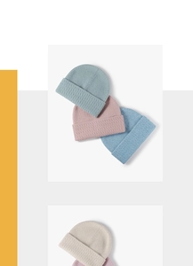 Close-up of knit beanie textures in pastel blue, pink, and cream with wide cuffs