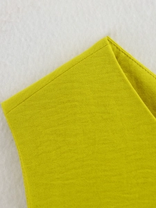 Vista macro della trama del tessuto giallo e delle cuciture sul top asimmetrico