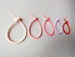 Macro view of five colorful silicone cable ties in different sizes on white background