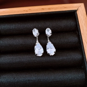 Detailed view of teardrop zircon earrings set in silver metal on black velvet display