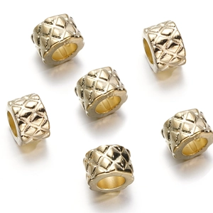 Detail of golden hollow cylinder beads featuring a quilted texture for jewelry making