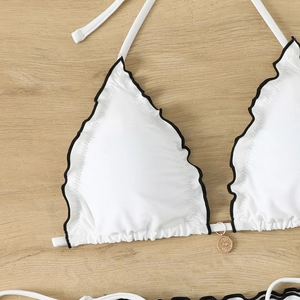 Detail of white halter bikini top with black scalloped edges and gold sun pendant