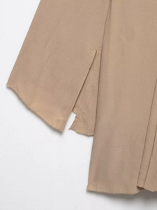 Detail of camel chiffon dress showing side slit design and stitched hemline texture